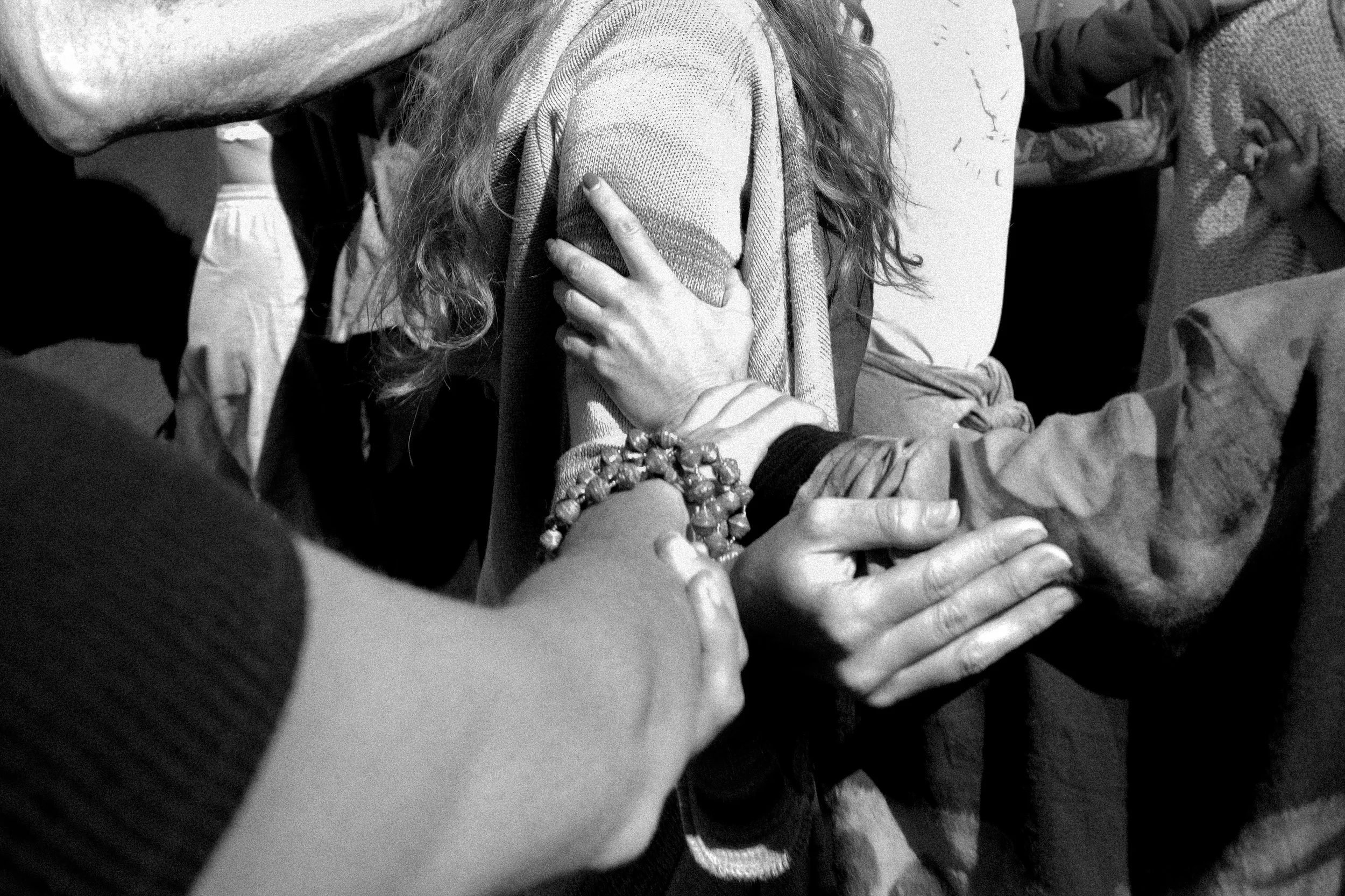 Hands holding and blessing a person during a listening circle — black and white intimate portrait.